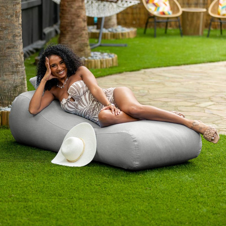 Jaxx Arlo outdoor bean bag lounger in Granite Sunbrella fabric styled on a backyard lawn for versatile patio comfort