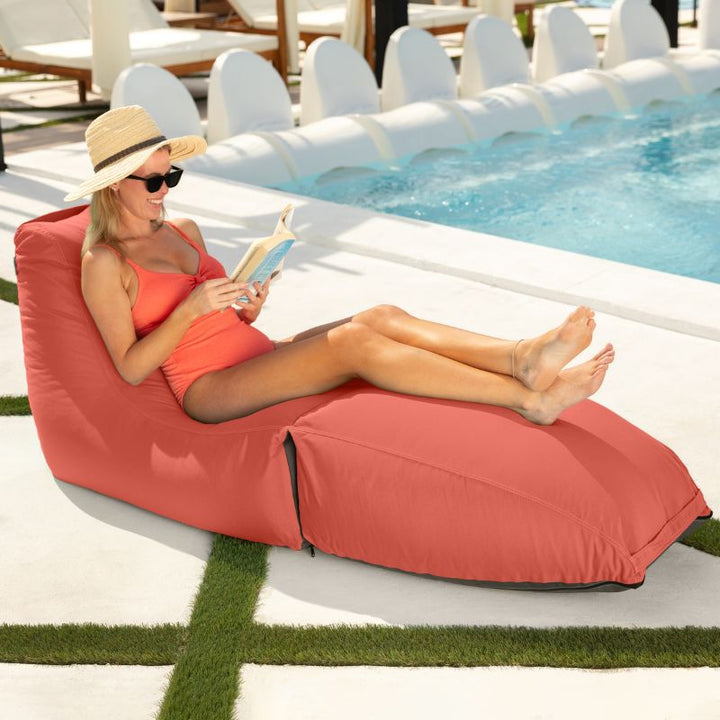 Woman reading poolside on the Prado outdoor bean bag lounger in Flamingo