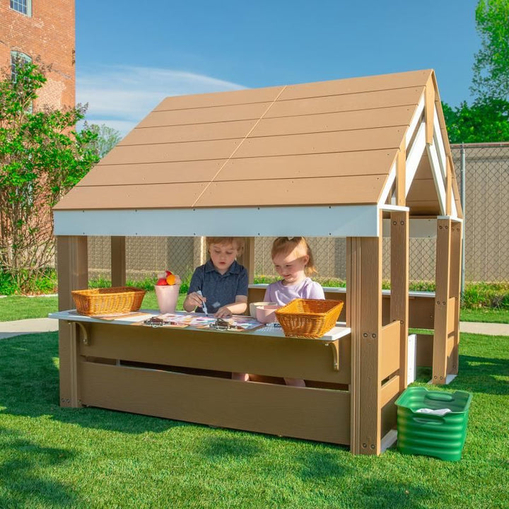 Two young children drawing side by side under the shaded roof of the Whitney Brothers outdoorED Learning Pavilion, a preschool outdoor learning shelter