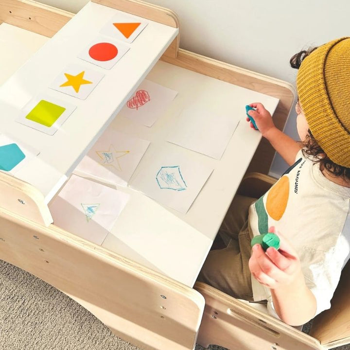 Top-down view of a child actively playing at the Sapiens Child Papaya Double Montessori Table and Chair Set, showing the enclosed table borders and child-height workspace for focused activity