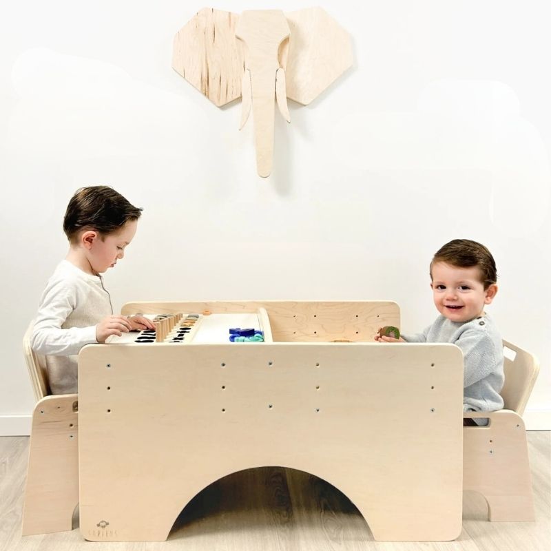 Two children sitting together at the Sapiens Child Papaya Double Adjustable Montessori Table and Chair Set, showing the independently adjustable chairs for siblings of different ages made in Vancouver Canada