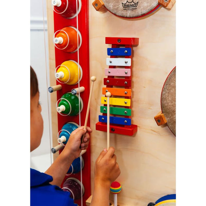 Close up of a child playing the xylophone and bells on the TFH Percussion Junction Wall Panel, a percussion wall panel for auditory sensory play