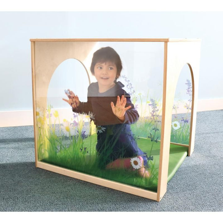 Child kneeling inside the Whitney Brothers Nature View Playhouse Cube with Mat, visible through the shatter-resistant wildflower acrylic wall of this quiet space