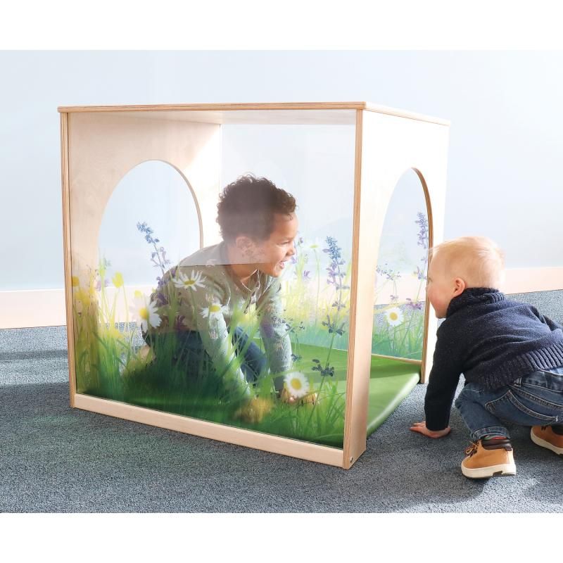 Two toddlers playing in the Whitney Brothers Nature View Playhouse Cube with Mat, a calm corner with wildflower acrylic walls and a green floor mat