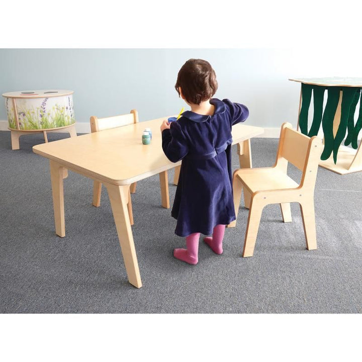 Child painting at the 22 inch Whitney Plus Rectangle Table by Whitney Brothers, a preschool rectangle table with natural wood chairs in a bright classroom
