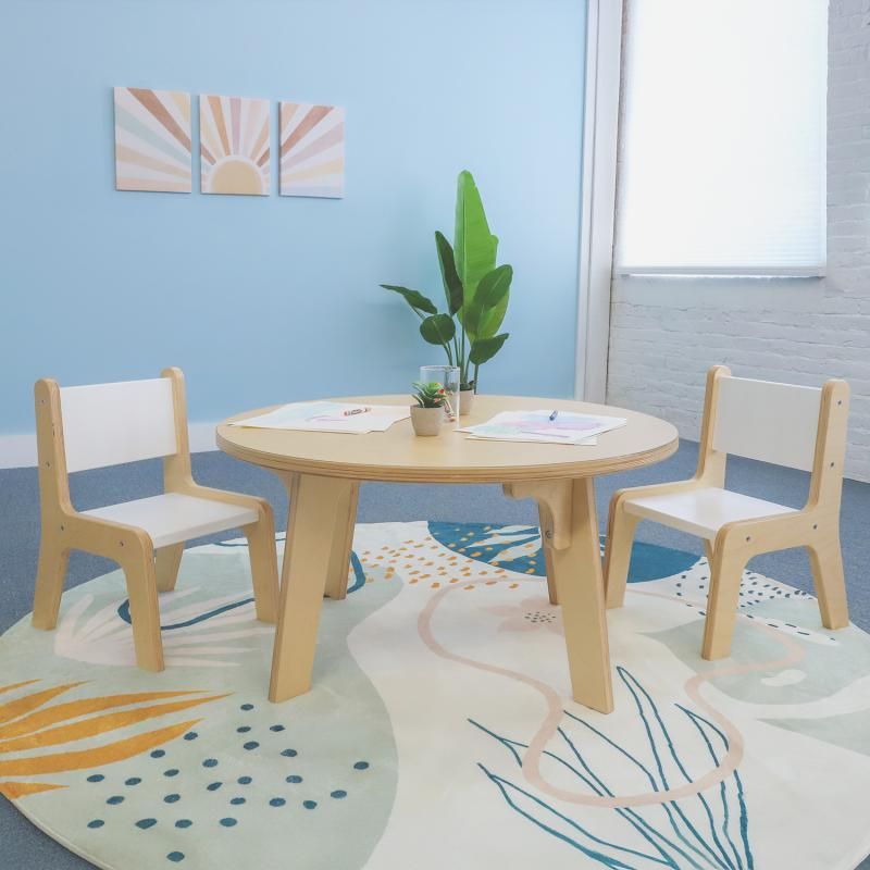 Whitney Brothers Whitney Plus Round Table at 18 inches high, a round classroom table with a maple top set with drawing paper and two children's chairs on a soft playroom rug