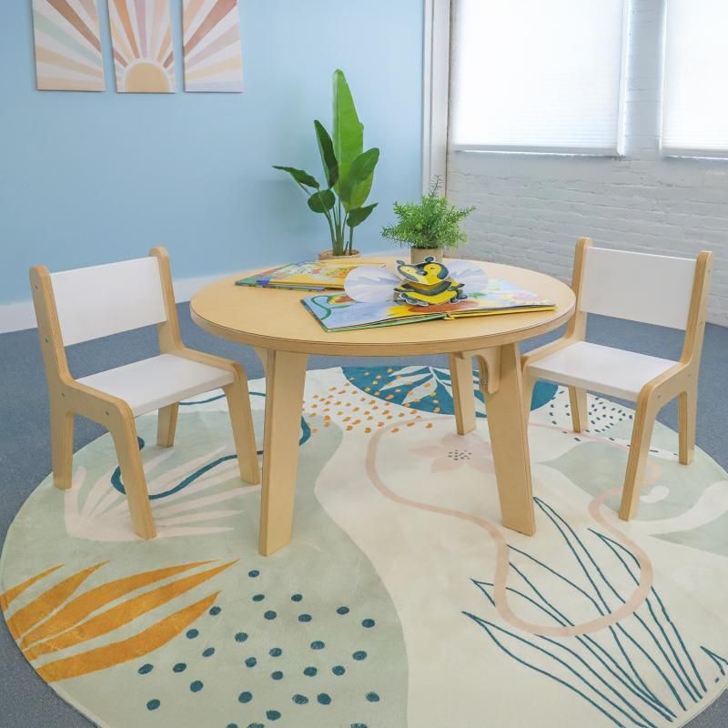 Whitney Brothers Whitney Plus Round Table at 20 inches high with picture books and two children's chairs, a round classroom table creating a cozy reading corner