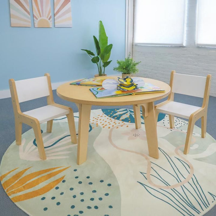Whitney Brothers Whitney Plus Round Table at 20 inches high with picture books and two children's chairs, a round classroom table creating a cozy reading corner