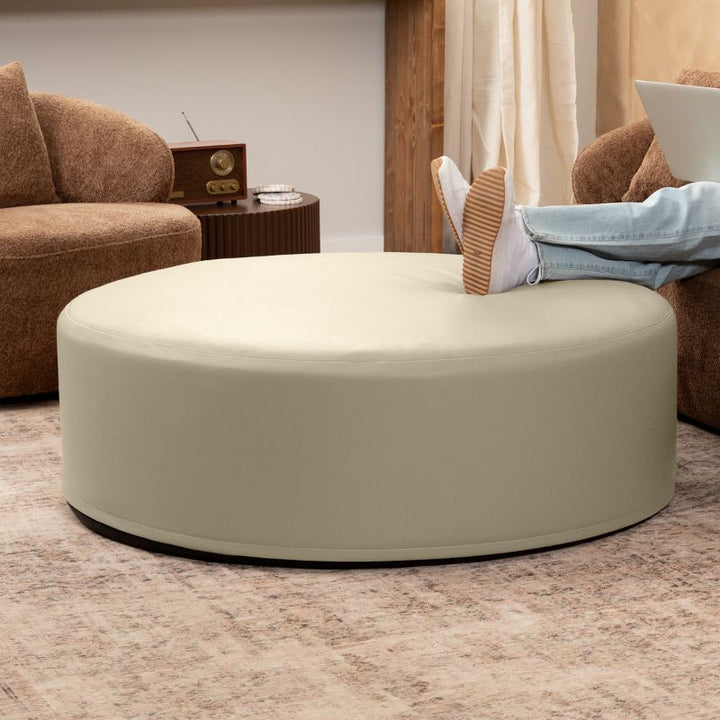 Jaxx Candler round ottoman in pale cream, flexible foam seating styled in a living room setting