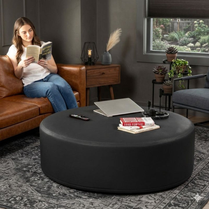 Jaxx Candler round ottoman in black, used as a coffee table alternative in a styled living room