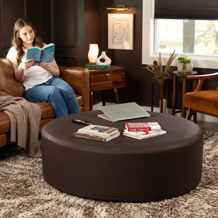 Jaxx Candler round ottoman in dark chocolate brown, used as a coffee table alternative in a styled living room