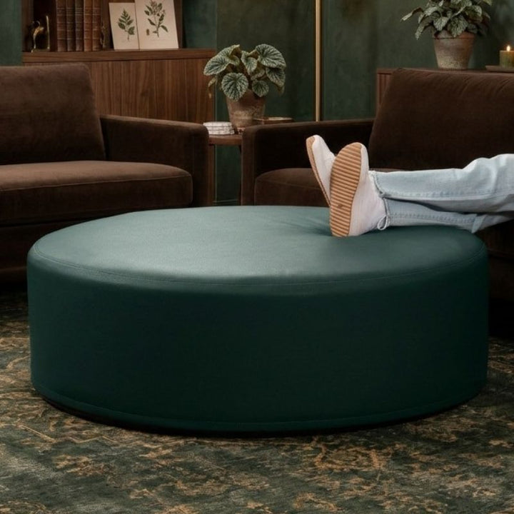 Jaxx Candler round ottoman in dark green, styled as a living room coffee table alternative and flexible seating