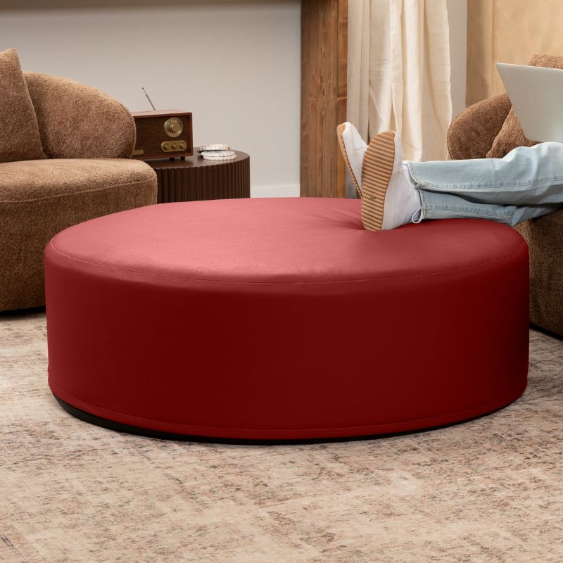 Jaxx Candler round ottoman in red, flexible foam seating styled in a living room setting