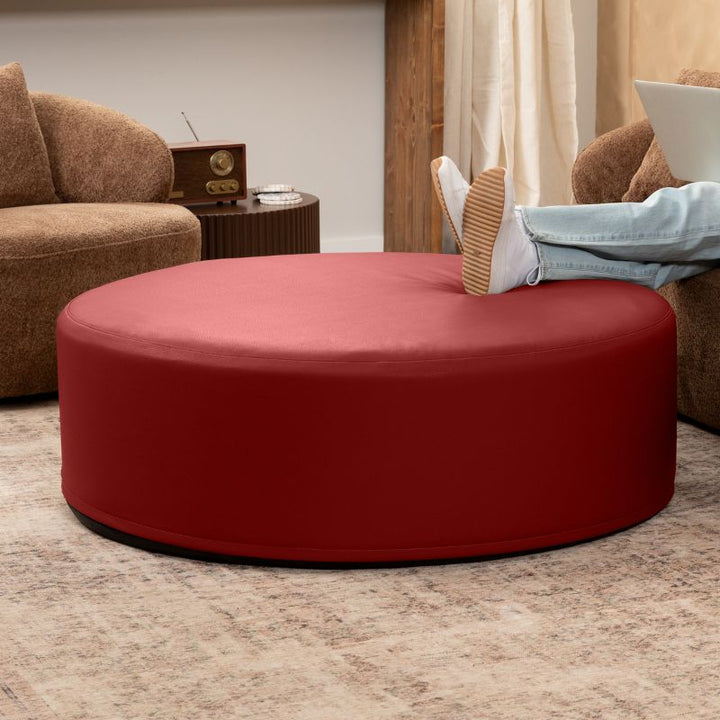 Jaxx Candler round ottoman in red, flexible foam seating styled in a living room setting