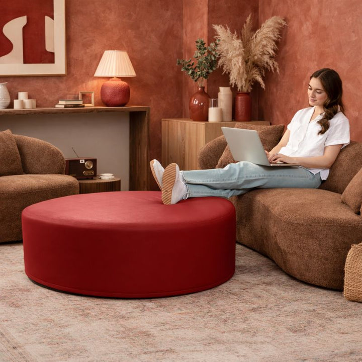 Jaxx Candler round ottoman in red, used as a coffee table alternative in a styled living room