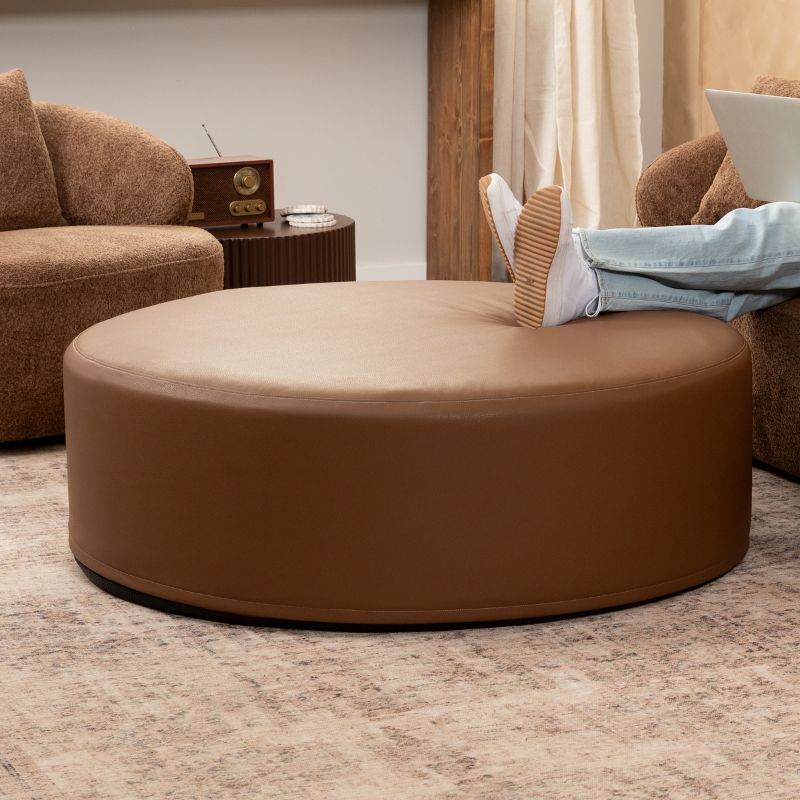 Jaxx Candler round ottoman in warm brown, flexible foam seating styled in a cosy living room setting