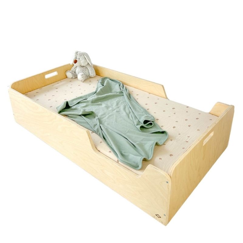 Sapiens Child Apple Montessori floor bed with rails in Birch plywood finish styled with a blanket, showing the cosy low-profile sleeping environment for toddlers across North America