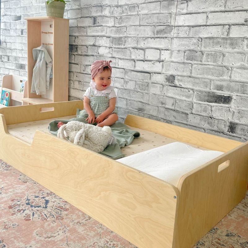 Second active play view of a child using the Sapiens Child Apple Montessori floor bed with rails, demonstrating the open entry point and child-centred sleeping space