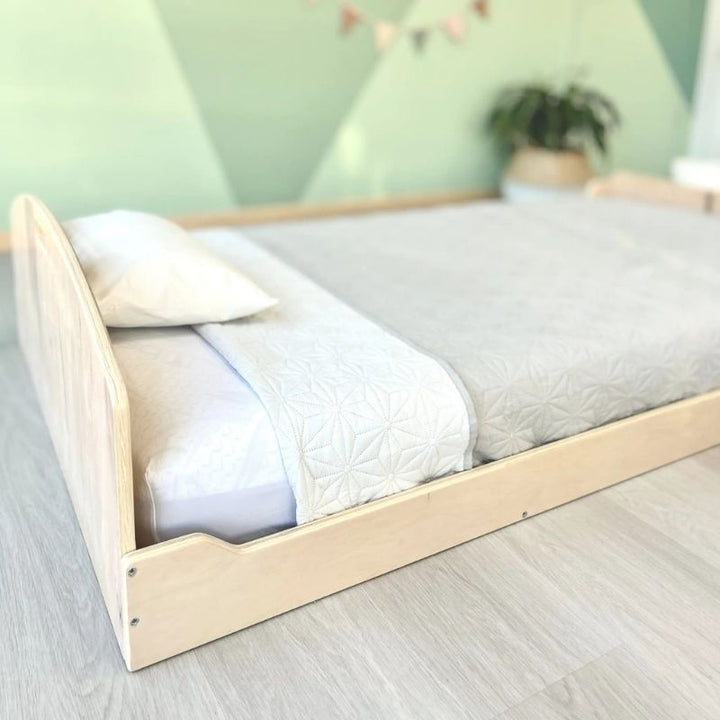 Close-up view of the Sapiens Child Cherry Twin Montessori floor bed in Maple finish, showing the smooth varnished edges and rounded corner safety detailing