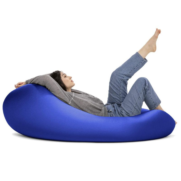 A woman reclines with her legs raised in the blue Jaxx Nimbus sensory bean bag chair, showing the stretchy cover in a relaxed lounging position