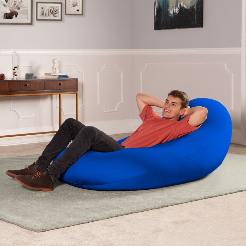 A man reclines in the blue Jaxx Nimbus sensory bean bag chair, showing upright support for relaxing at home