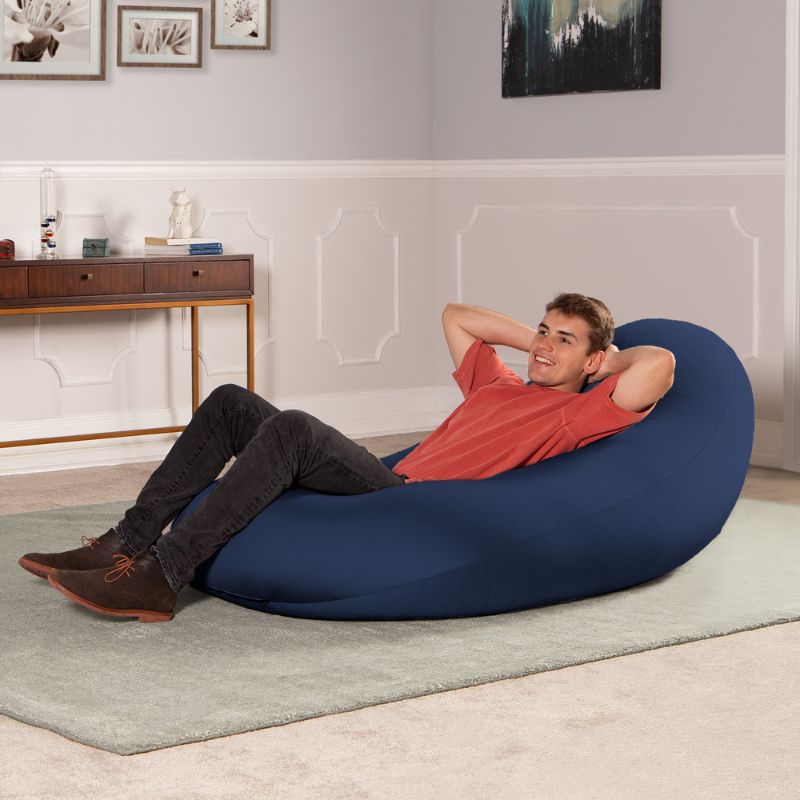 A man reclines in the navy Jaxx Nimbus sensory bean bag chair, showing flexible sensory seating for the home