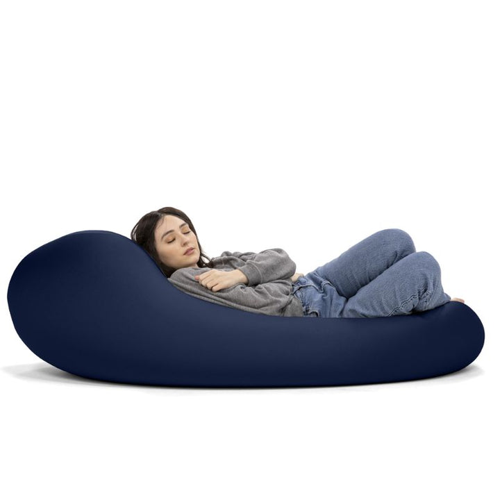 A woman rests in the navy Jaxx Nimbus sensory bean bag chair, showing the flexible seating chair in its flat lounging position