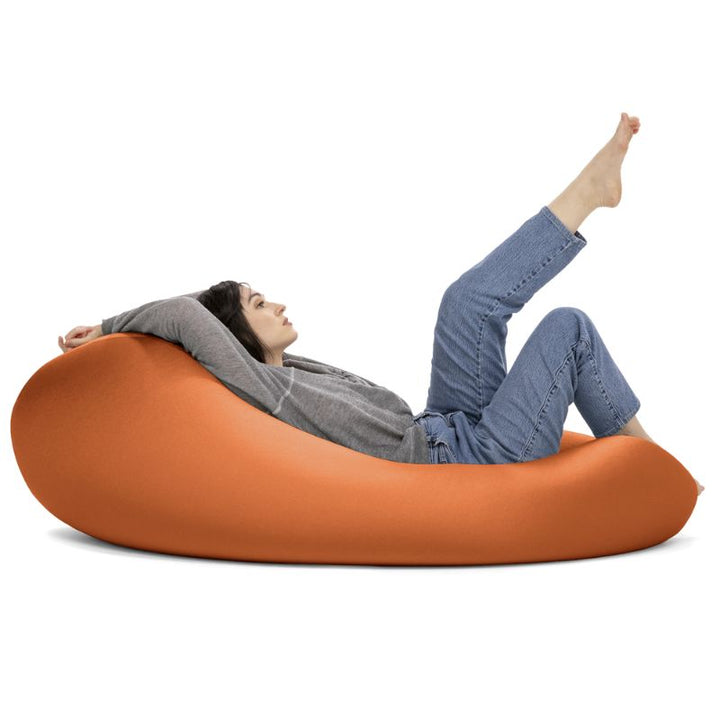 A woman reclines with her legs raised in the orange Jaxx Nimbus sensory bean bag chair, showing flexible sensory seating in a relaxed position