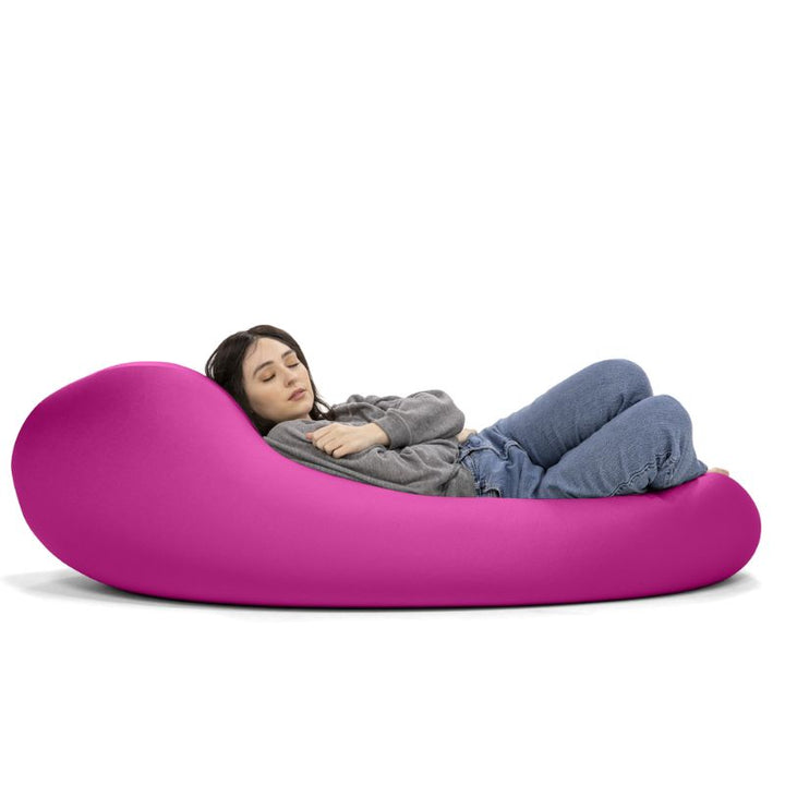 A woman rests in the pink Jaxx Nimbus sensory bean bag chair, showing the flat, flexible seating position of this stretchy spandex chair