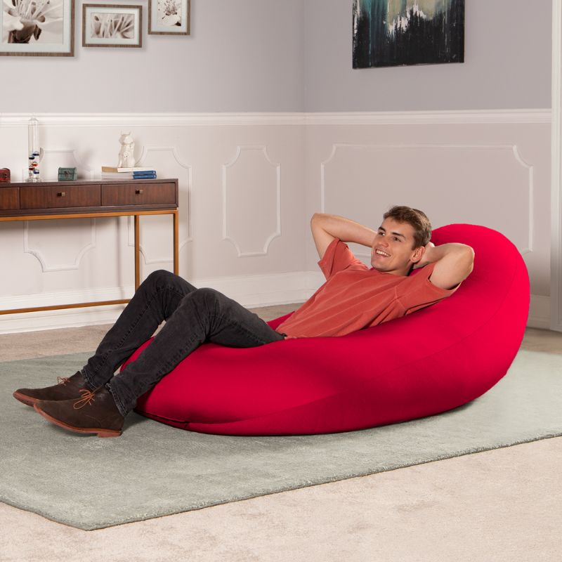 A man reclines in the red Jaxx Nimbus sensory bean bag chair, showing the stretchy cover as upright home seating