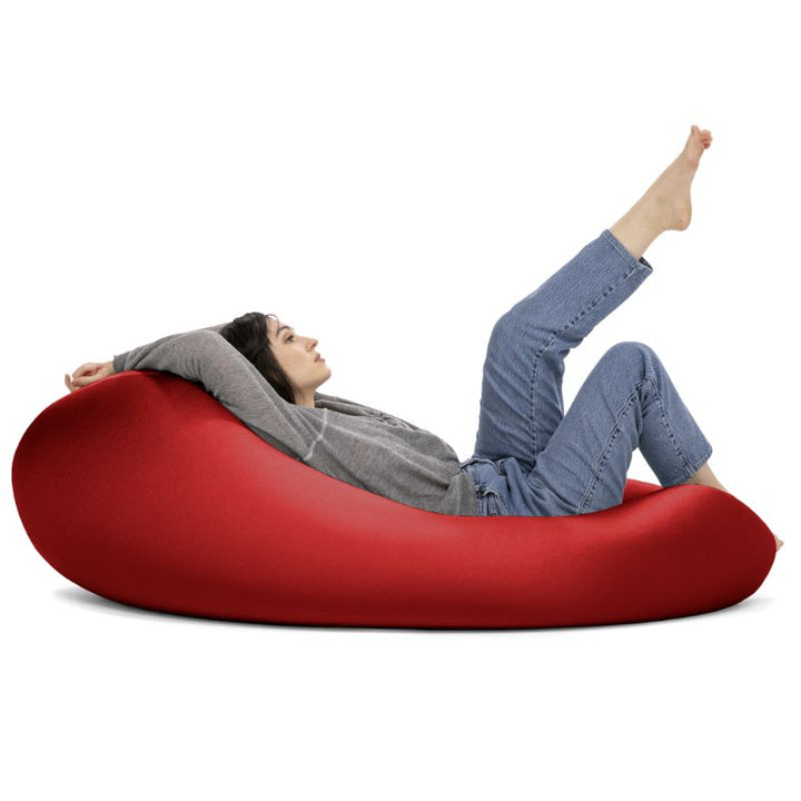 A woman reclines in the red Jaxx Nimbus sensory bean bag chair, showing how the stretchy cover adapts to a flat lounging position
