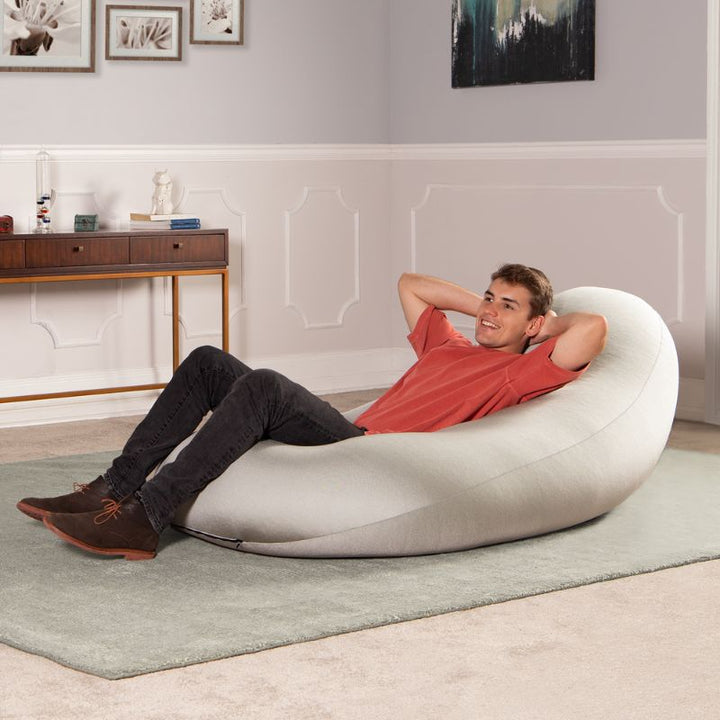 A man reclines in the light gray Jaxx Nimbus sensory bean bag chair, showing upright support for relaxing at home