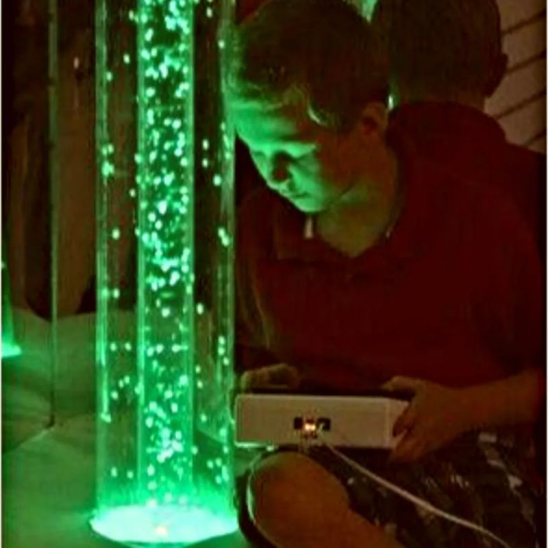 Boy holding a control unit to change the colour of the TFH Interactive LED Bubble Tube, interactive sensory light play that builds focus and engagement