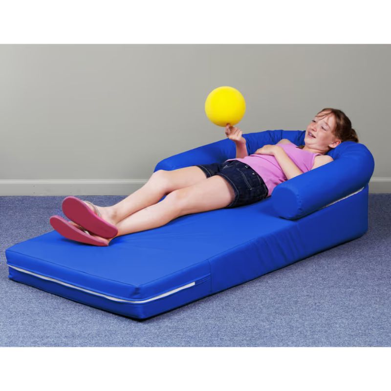 TFH Long Easy Comfort Lounger in blue with a child reclining and reaching for a ball, a sensory foam lounger supporting body awareness and proprioceptive play