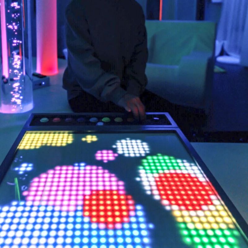 Bright multicolour LED pixel patterns filling the TFH Pixels Pro Illumination Panel as a user presses its buttons, interactive visual sensory play