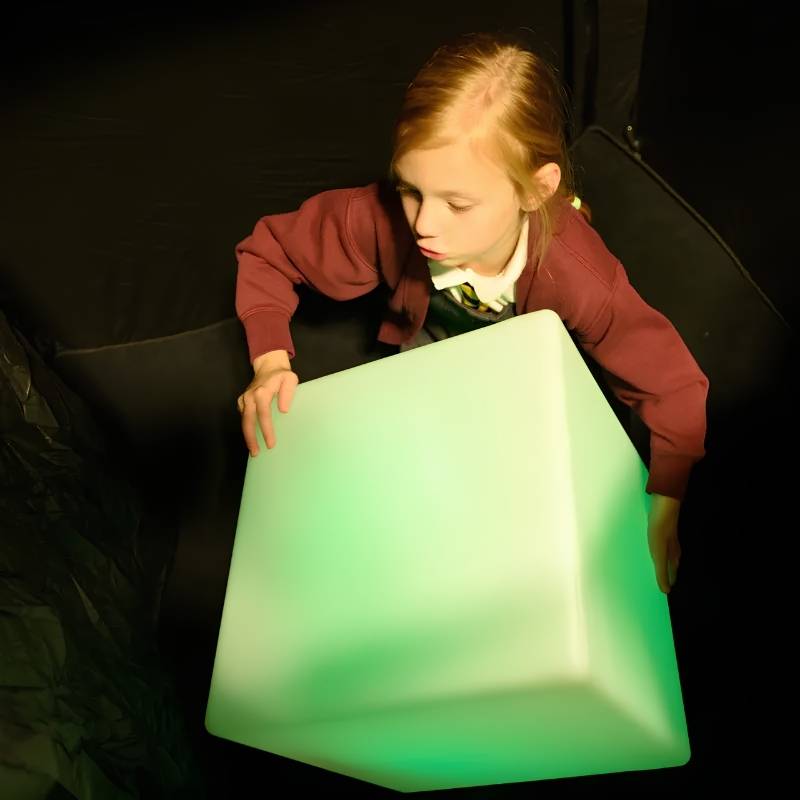 Close overhead view of a child turning the TFH Mood Dice sensory mood cube as it glows a soft green colour
