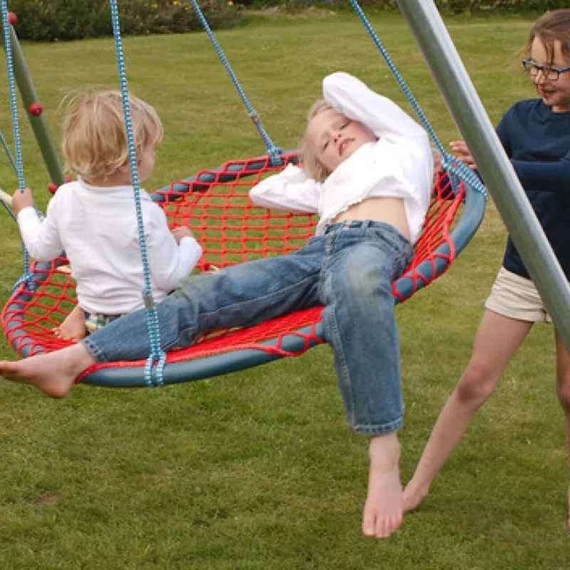 Two children swinging together on the TFH Nest Swing outdoors, a sensory swing built for vestibular play and shared fun