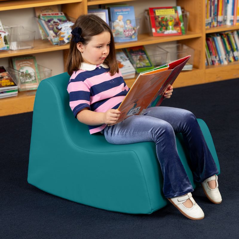 A child reading in the teal Jaxx Midtown Rocker, a sensory rocking chair for kids in a school library