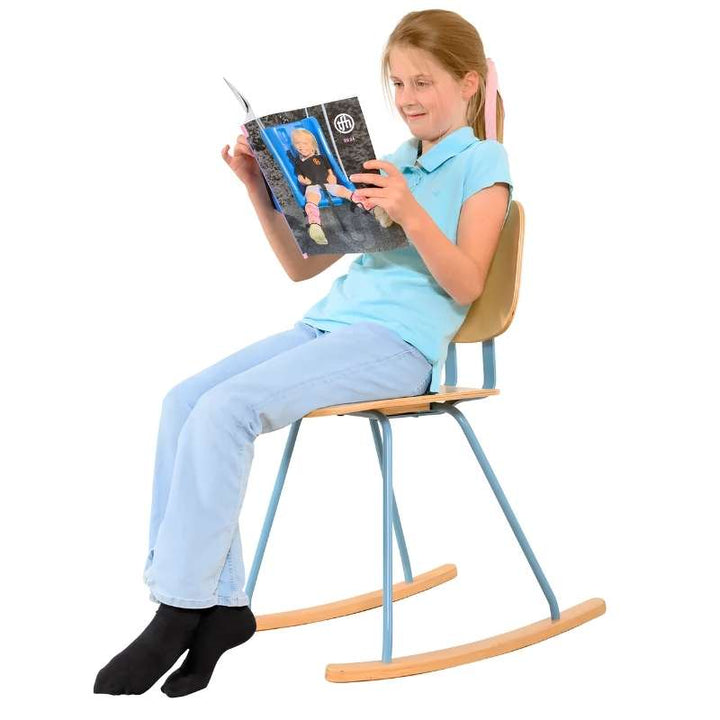 Child using the TFH Mindflow Rocking Chair for focus while reading, a sensory rocking chair supporting calm seated movement. PLACEHOLDER - confirm final image before uploading, as a third-party product catalog is visible in the child's hands.