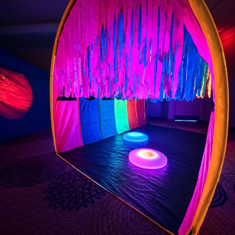 TFH Giant Tickle Me Tunnel with hanging rainbow ribbons and glowing floor lights, a sensory tunnel for tactile exploration in multi-sensory rooms