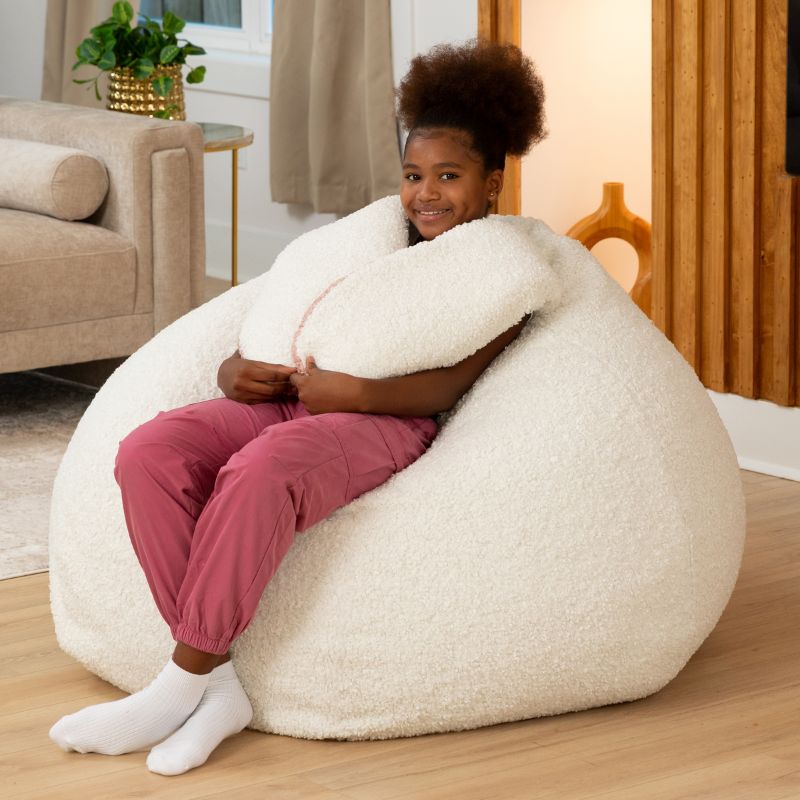 a child hugs the plush ear of the Cloud Raven-Symoné HopSeat sherpa bean bag chair, showing its soft tactile texture