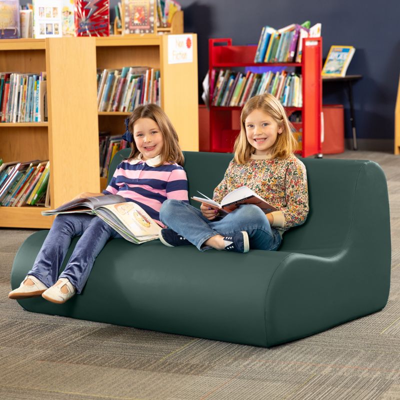 Two children reading on a sequoia green Jaxx Midtown soft seating couch in a school library calm corner