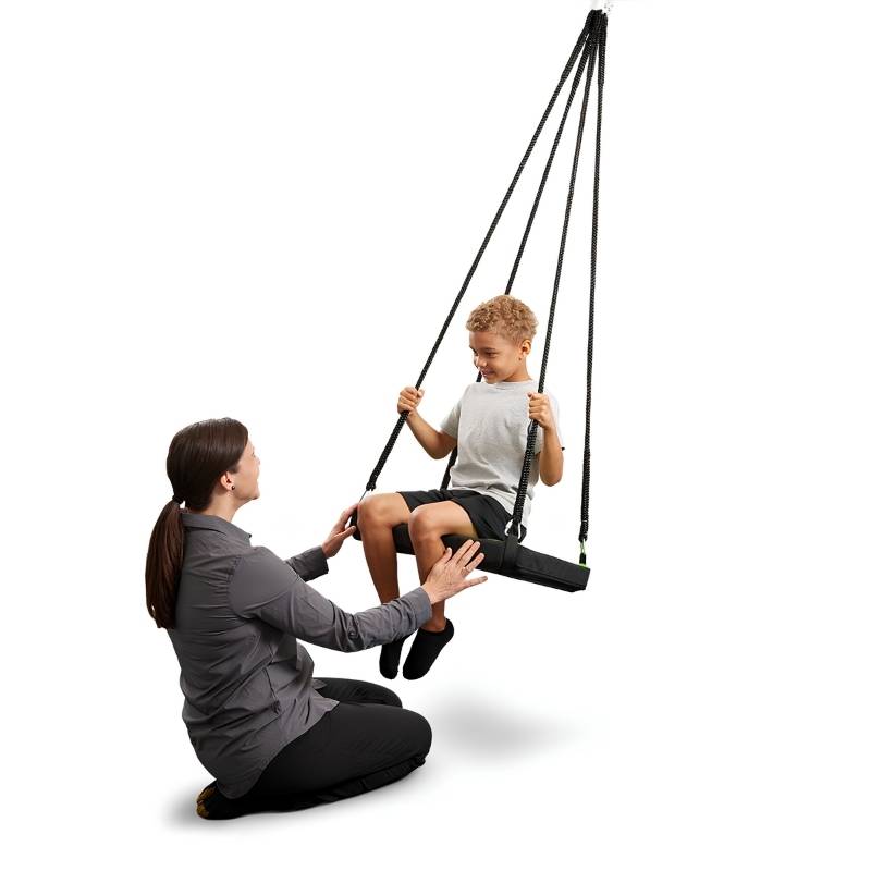 Child on the Southpaw Soft-Lite Junior Glider with adult preparing to initiate movement, showing how the vestibular platform swing supports guided sensory integration therapy