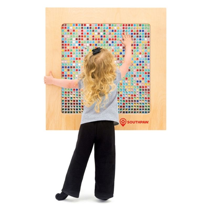 Girl interacting with the Southpaw Marvelous Marble Panel sensory wall panel, exploring iridescent marbles through tactile and visual sensory play in a therapy or home setting
