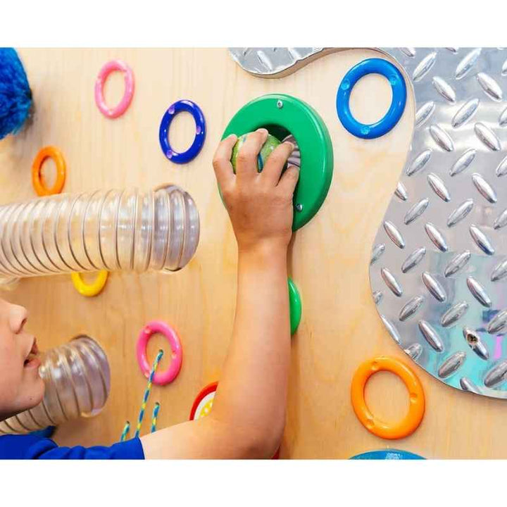 Close-up of a child's hand exploring a textured mirror ring on the TFH Tactile Loopie Wall sensory wall panel