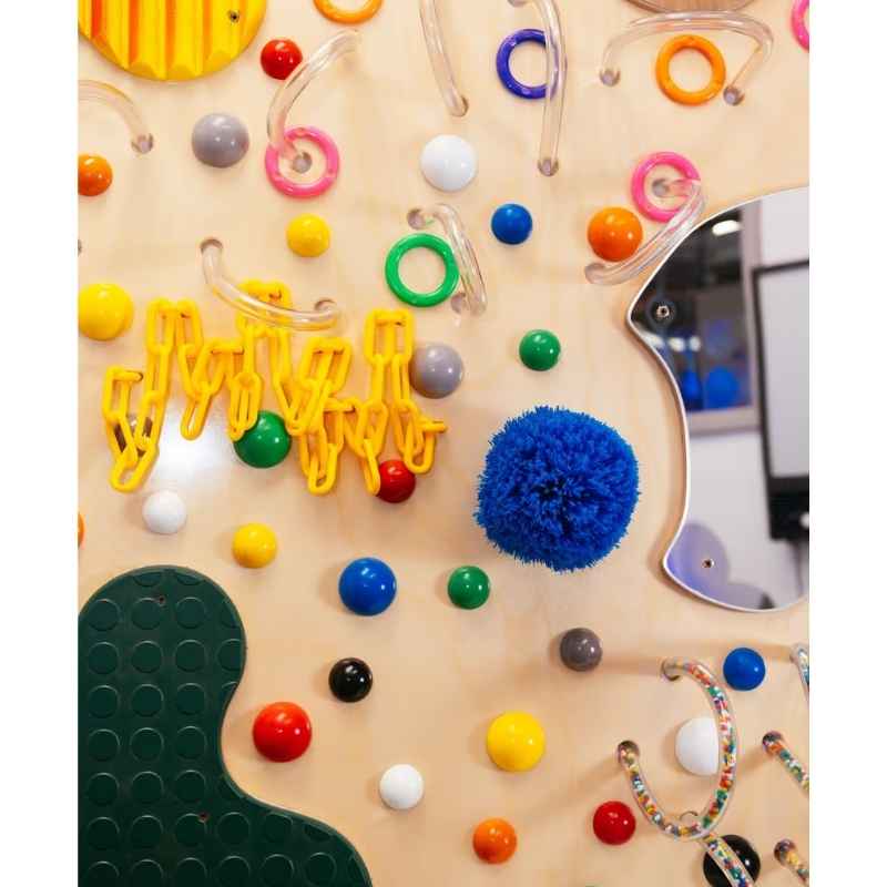 Close detail of the TFH Textured Wall Panel showing pom-poms, rings, beads and a mirror insert on this textured sensory wall panel