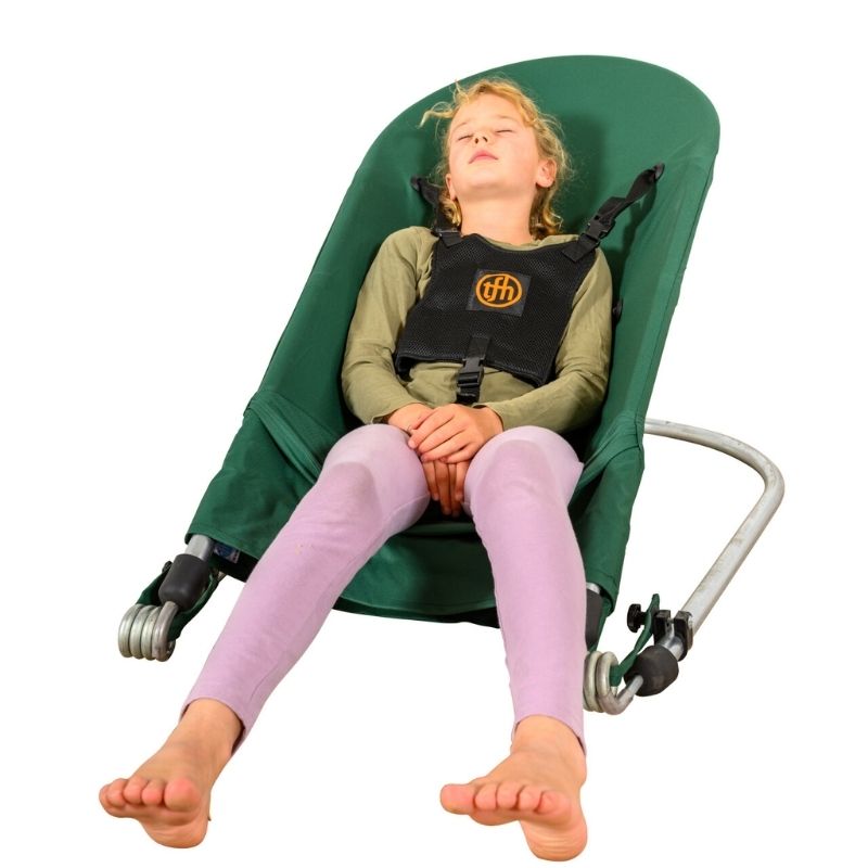 Child resting in the TFH Bouncing Chair Large & Deep green variant, showing the supportive proprioceptive seating position with harness