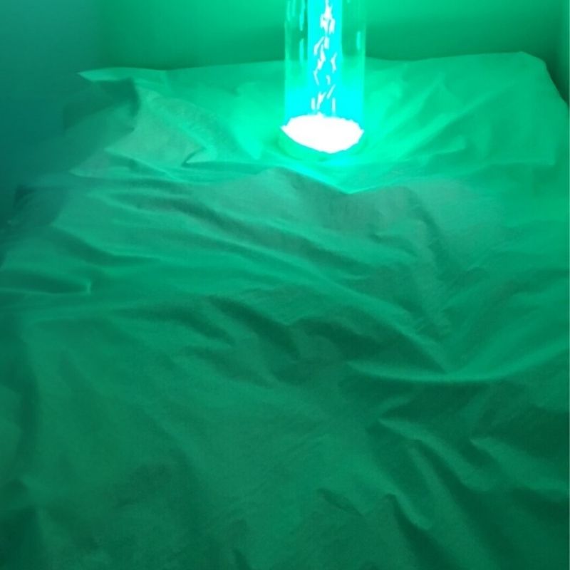 TFH Bubble Tube Cuddle Cushion in a sensory room with green LED bubble tube light, showing the full 40-inch by 60-inch soya foam beanbag cushion for immersive sensory room seating