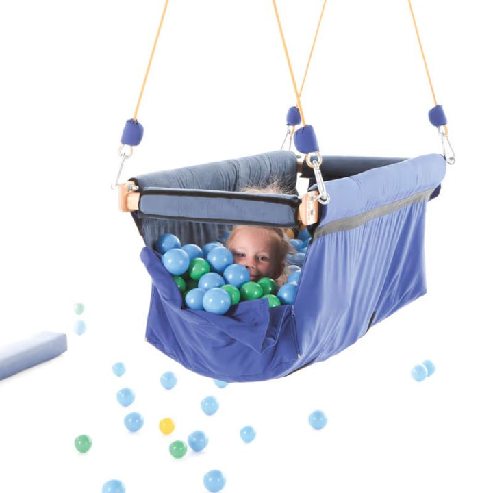 TFH Deep Boat Swing hanging from padded rope supports, an enclosed vestibular sensory swing filled with colourful balls for deep pressure play