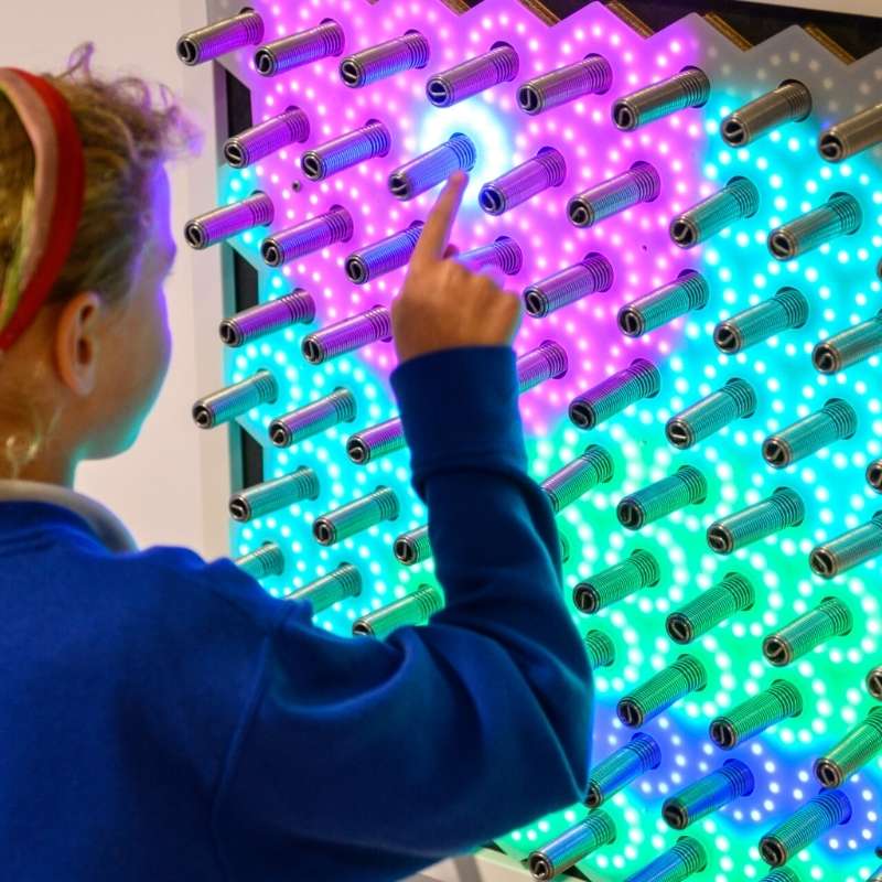 Child touching the TFH Electro Wobble Garden Activity Panel showing immediate LED light response to spring-sensor contact for interactive tactile sensory exploration